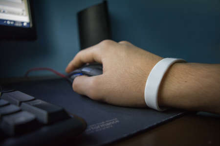 Male hand with bracelet holding computer mouse