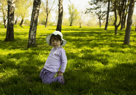 cute small girl sitting in  grass park の写真素材
