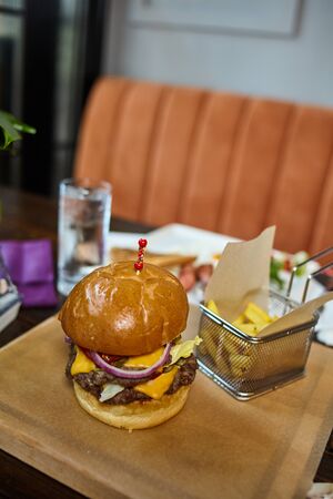 Dish presentation - traditional american burger with fries on a stylish wooden underlay. Restaurant interior backgroundの写真素材