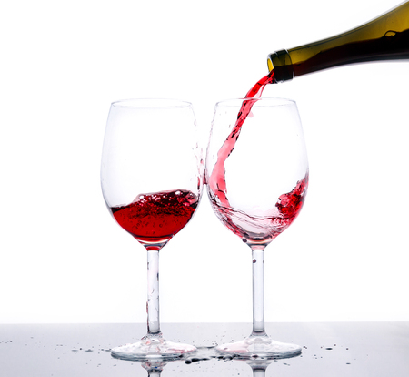 Red wine pouring down from a bottle isolated on whiteの写真素材