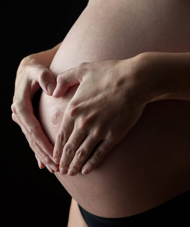 Heart shape - pregnant woman with black backgroundの写真素材