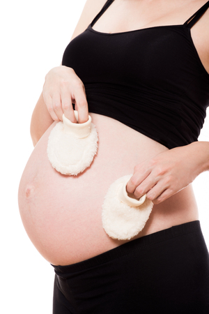 Pregnant woman holding a pair of baby booties isolatedの写真素材