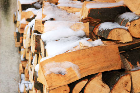 Stacked firewood in winter under the snow