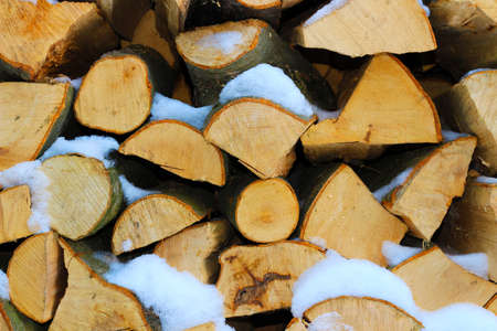 Stacked firewood in winter under the snowの写真素材