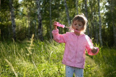 Little girl blowing soap bubbles in the forestの写真素材