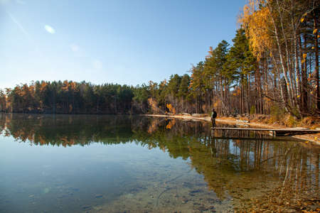 A man admires the landscape of a mountain lake while standing on the pierの写真素材