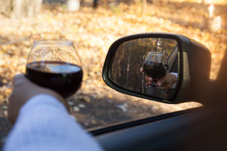 The girl at the wheel is drinking alcohol. Traffic safety threatの写真素材