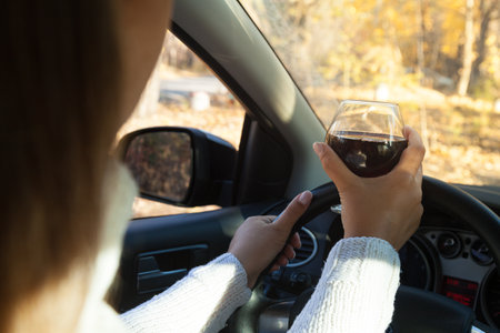 The girl at the wheel is drinking alcohol. Traffic safety threatの写真素材