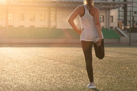 Sports girl doing stretching on the stadium lawnの写真素材
