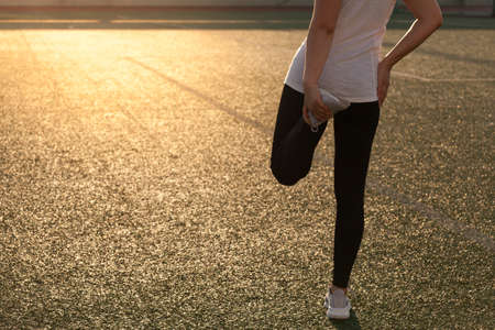 Sports girl doing stretching on the stadium lawnの写真素材