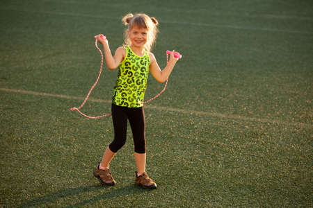 Little girl jumping rope on the stadium lawnの写真素材