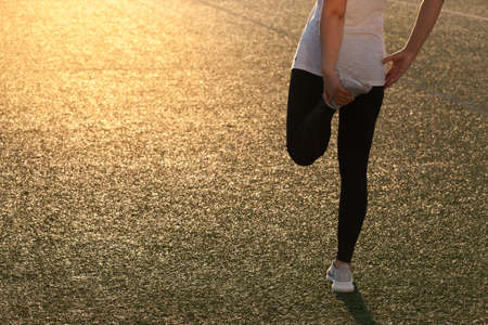 Sports girl doing stretching on the stadium lawnの写真素材