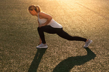Sports girl doing stretching on the stadium lawnの写真素材