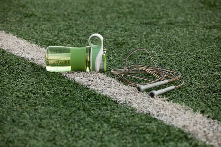 A bottle and a skipping rope lie on the green grass of the stadiumの写真素材