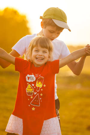 Children play an airplane and laugh against the backdrop of the setting sunの写真素材