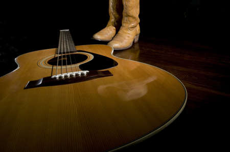 Selective focus on the guitar in the foreground with cowboy boots in the backgroundの写真素材
