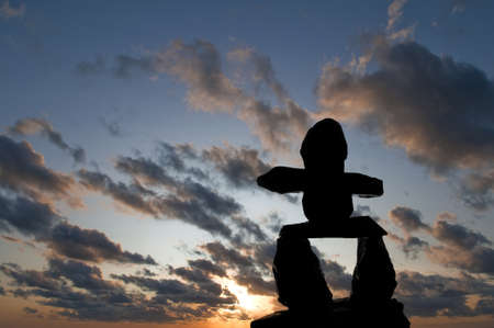 Selective focus on the Inukshuk silhouette in the foreground with sunset in the backgroundの写真素材