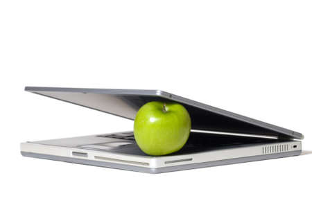 Laptop closing on a green apple - selective focus on the apple.の写真素材