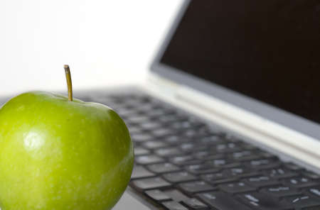 Macro shot with selective focus on green apple in the foreground with laptop in the background.の写真素材