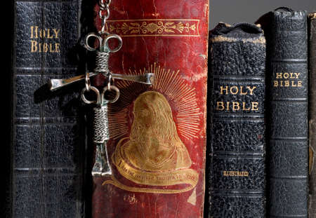 Spine view of multiple bibles with the nail cross hanging in the front.