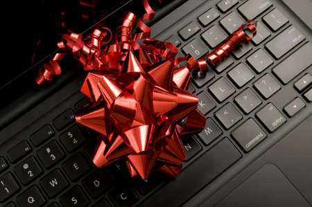 Red Christmas ribbon on black laptop keyboardの写真素材