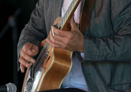 Selective focus on the hands of a guitarist playing acoustic slideの写真素材