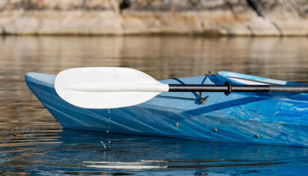 Selective focus on the paddle and kayak with water drops hitting the calm lakeの写真素材