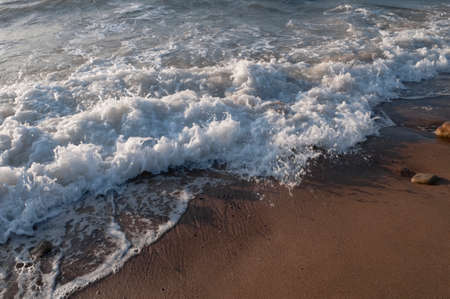 Selective focus on the foreground sand at the beach with the waves crashing in