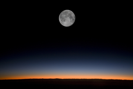 Moon over horizon at sunset from plane at high altitudeの写真素材