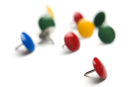 Thumb tacks isolated on white with extreme selective focus on one.