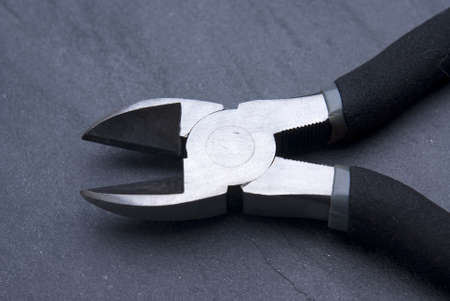Metal wire cutters contrasted with a grey slate background.の写真素材