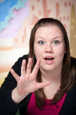 Pretty young business woman raises her hand in surprise when given surprising news.