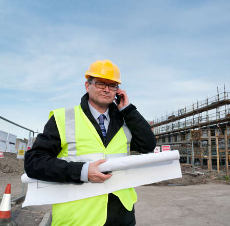 Architect or engineer at work on a building site. Holding plans for construction work. Confident...