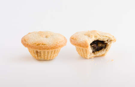 Two fruit pastries, one partially eaten with the fruit revealed. Know in Britain as mince or mincemeat pies. Popular at Christmas. Focus on front of pies.の写真素材