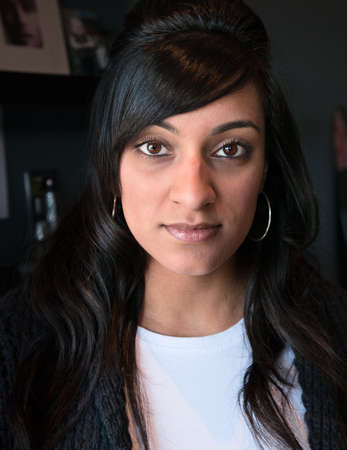 Close up portrait of a lovely young Indian woman looking confidently at the camera with a slight...