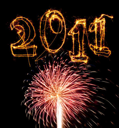 Year 2011 written in sparklers above bright pink fireworks explosion. Use for celebrations like New...