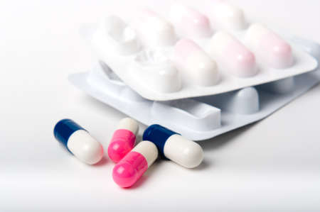 Blue and pink pharmaceutical capsules with blister packs on white close upの写真素材