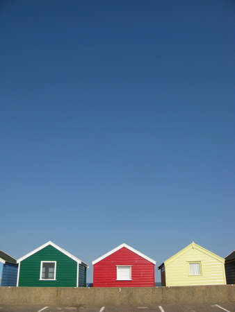 Green, red and yellow beach huts on sunny day in Southwold, Suffolk, England, UKの写真素材