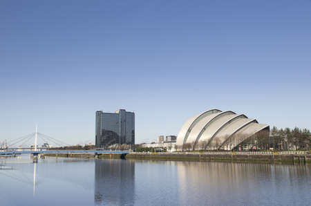 River Clyde in Glasgow with bridge, auditorium and modern buildings in sunshine with blue skyのeditorial素材