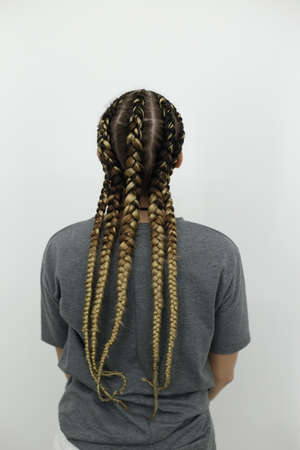 The girl stands with her back against a light background, thick