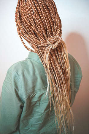 Extreme close up beauty portrait of young african woman showing long braided hair next to face.