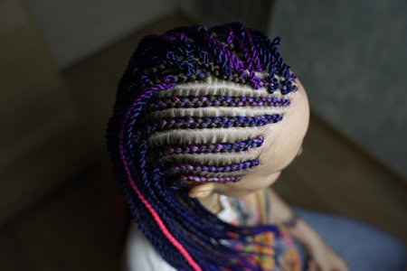 The master demonstrates to students how to weave an African braid with Kanekalon on a model, afro-locks on a frame, frame hairstyles, afro-curls, a base for hair extensions, a thin braid braided over a girl head, Senegalese braids on a frameの写真素材