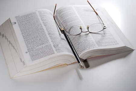 open book, reading glasses with pencil on a tableの写真素材