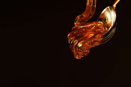 Honey drop with gold color isolated on black stock photoの写真素材