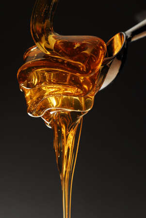 Golden honey spilling on black stock photoの写真素材