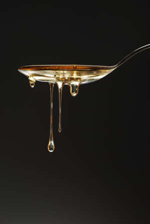 Golden honey drops over the spoon stock photo