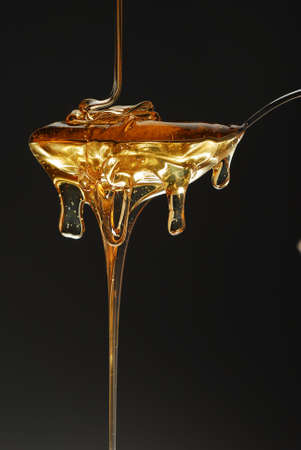 Golden honey spilling over black background stock photoの写真素材