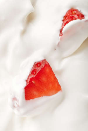 A strawberry cut in half in white vanilla yoghurtの写真素材
