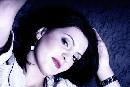Girl lying on a rough wall blue shiftの写真素材