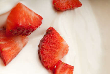 Juicy red strawberry pieces floating in creamの写真素材